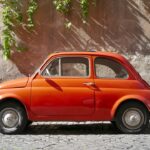 an orange car parked on a cobblestone street