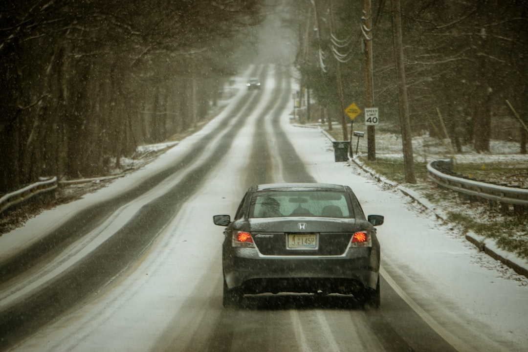 black car on road covered with snow during daytime